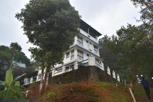 uma casa branca no topo de uma colina em MUNNAR TENT HILLS RESORT em Devikolam
