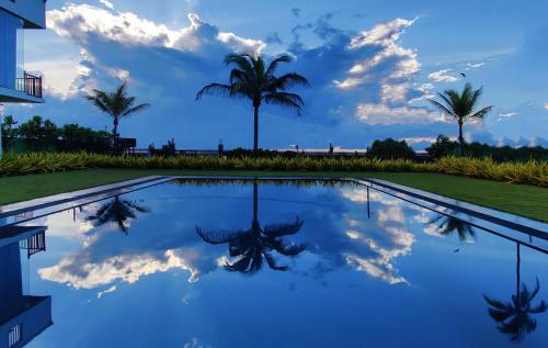 a reflection of the sky and palm trees in a pool at Calypso Sunset in Iranawila