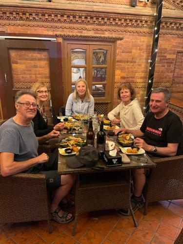 a group of people sitting around a table eating food at Hotel Empire & Rooftop Restaurant in Bhaktapur