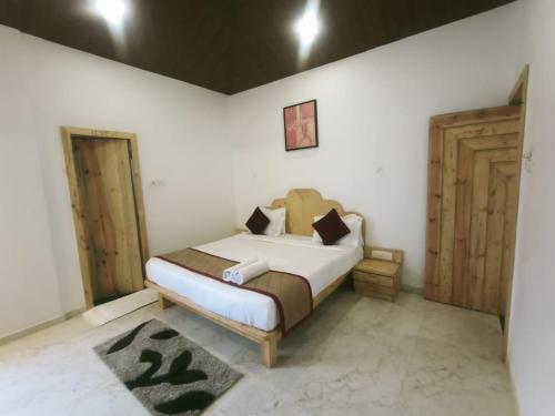1 dormitorio con 1 cama y 2 puertas de madera en Royal Resort Villa, en Mahabaleshwar