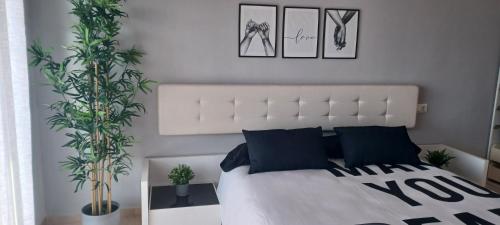 ein Schlafzimmer mit einem weißen Bett und zwei Pflanzen in der Unterkunft Sunset Apartment Aguadulce in Aguadulce
