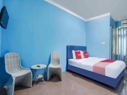 a bedroom with blue walls and a bed and chairs at OYO 91005 Cottage Putra Mutun Beach in Bandar Lampung