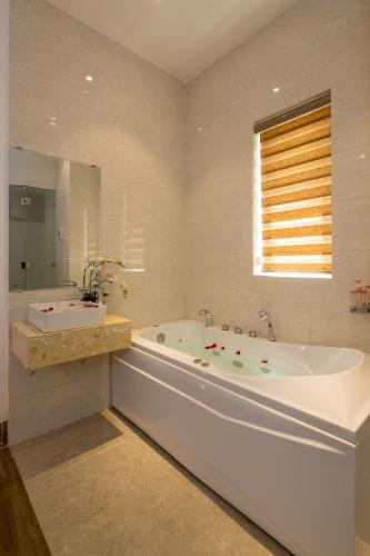 a large bathroom with a tub and a sink at Roliva Hotel & Apartment Danang in Danang