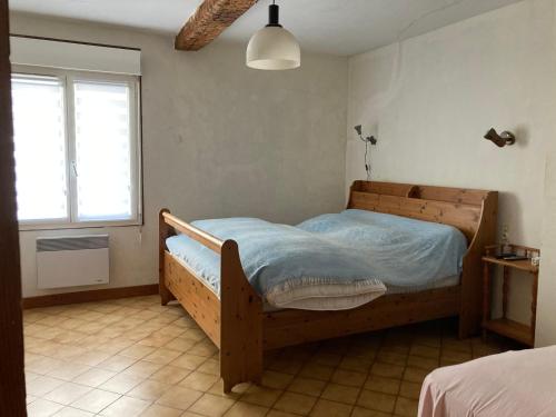 um quarto com uma cama de madeira e uma janela em La corderie em Sigean