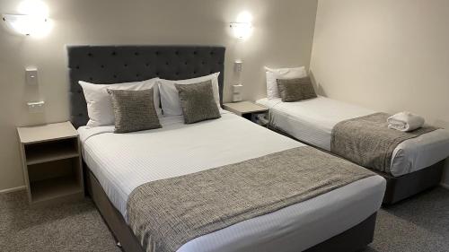 a hotel room with two beds and two lamps at Rocky Gardens Motor Inn Rockhampton in Rockhampton