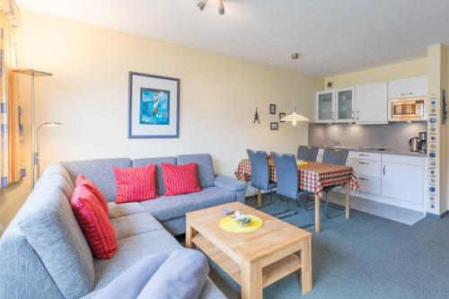 ein Wohnzimmer mit einem Sofa und einem Tisch sowie eine Küche in der Unterkunft Vogelsand 321 in Cuxhaven
