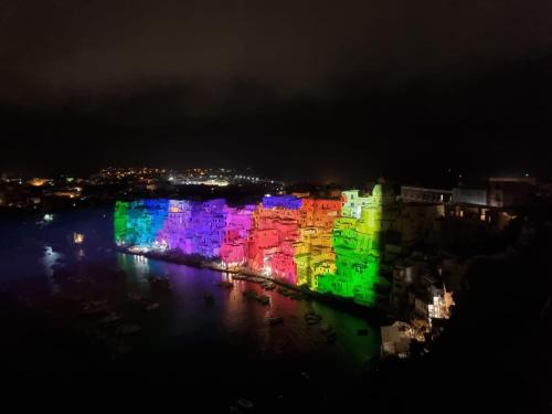 a lit up building on the water at night at La casa del postino in Procida