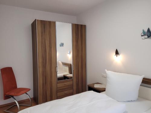 a bedroom with a mirror and a bed and a chair at Ferienwohnungen Stranddistel - Apartments von 30 bis 75 qm in Zinnowitz