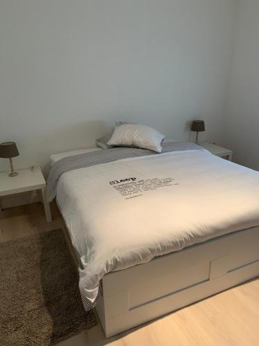 a bed in a room with two night stands and two lamps at Gallery Apartment in Blankenberge