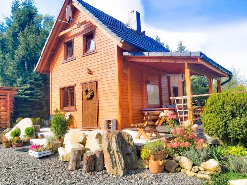 une petite maison en bois avec une terrasse couverte et quelques plantes dans l'établissement Wierzbowy Jar - Natura Spokój Sauna Kominek Karkonosze, à Janowice Wielkie