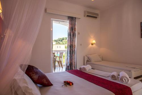 a white bedroom with a bed with a window at ALADDIN TSILLIVi in Tsilivi