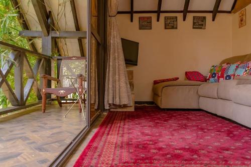 a living room with a couch and a red rug at The Annex at 64 : Cozy, rustic cottage/treehouse in Nairobi