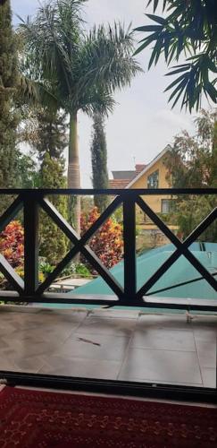 a view of a fence with palm trees in the background at The Annex at 64 : Cozy, rustic cottage/treehouse in Nairobi