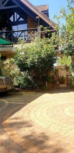 a house with a brick driveway in front of a building at The Annex at 64 : Cozy, rustic cottage/treehouse in Nairobi