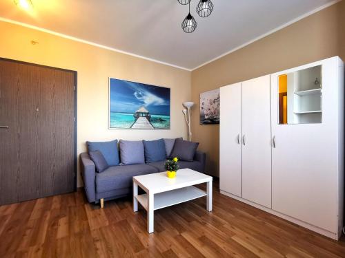 ein Wohnzimmer mit einem blauen Sofa und einem Tisch in der Unterkunft Euro24 Apartamenty Rumia Klon - studio z balkonem in Rumia