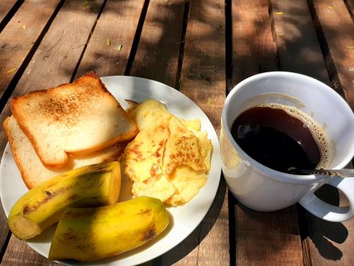a plate of breakfast food with toast and a cup of coffee at The Nest Haven Hostel in Dar es Salaam