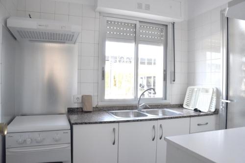 Una cocina blanca con fregadero y ventana. en Apartamentos Las Rosas, en Denia