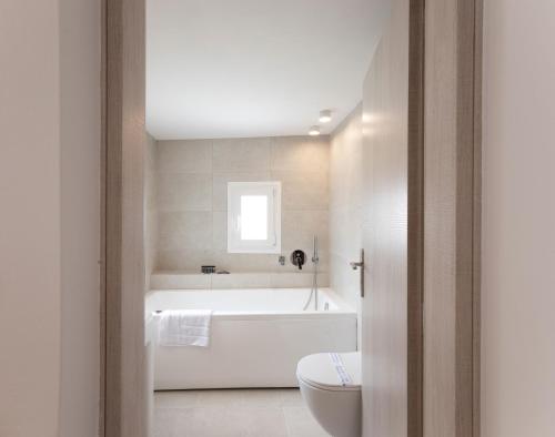 a white bathroom with a tub and a toilet at Mylos Suites in Mikonos