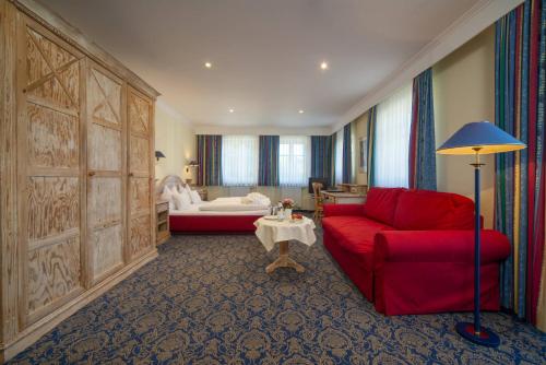 a living room with a red couch and a bedroom at Aktiv Hotel Schweiger in Füssen