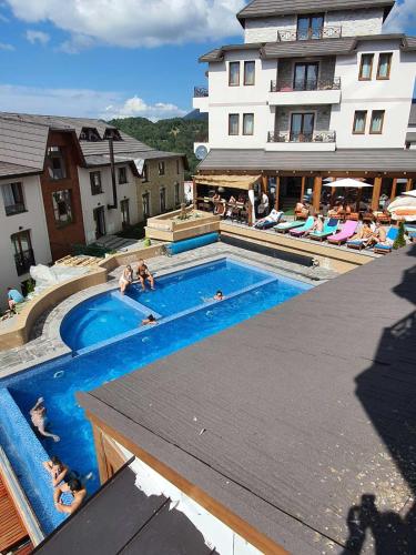 a large swimming pool with people sitting in chairs around it at L&N Apartmani Kopaonik-Milmari Resort in Kopaonik