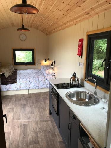 a kitchen with a sink and a bed in a room at Sunset Shepherds Hut in Taunton