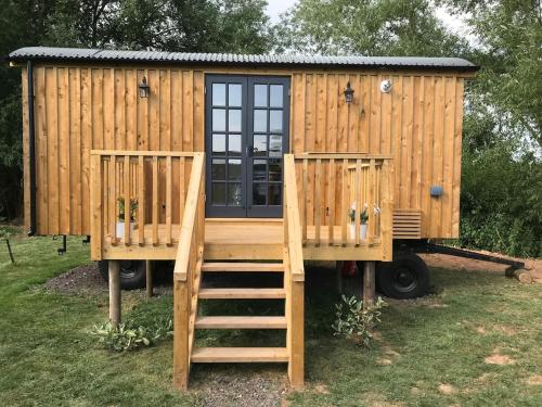 a wooden cabin with a staircase leading up to it at Sunset Shepherds Hut in Taunton