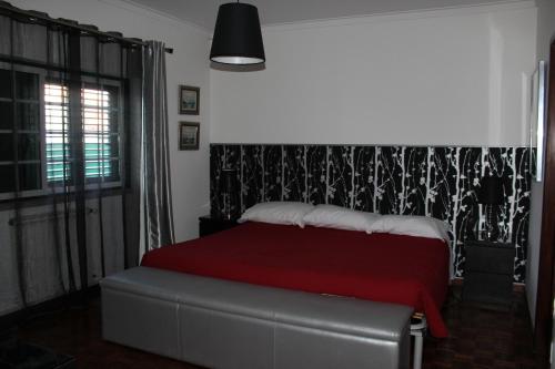 a bedroom with a bed with a red blanket at Hostel Casa Lucas in Charneca