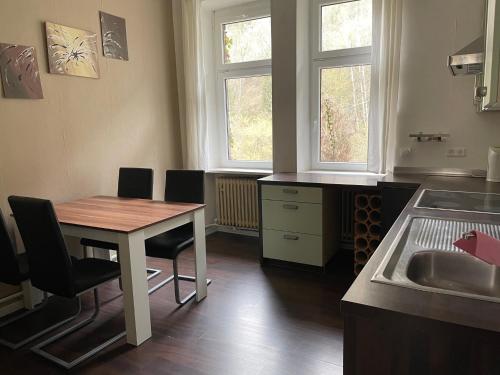 Una cocina con mesa y sillas y dos ventanas. en Ferienwohnung an der Sesselbahn, en Cochem