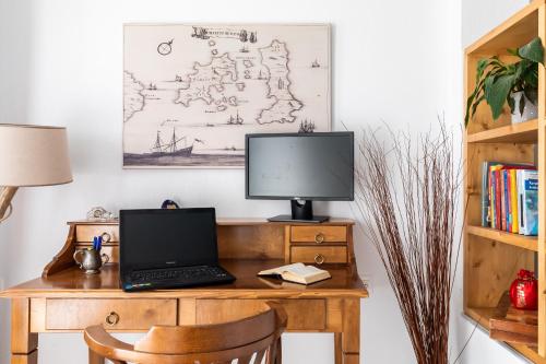 a desk with a laptop and a monitor on it at Sokaki Home in Skopelos Town