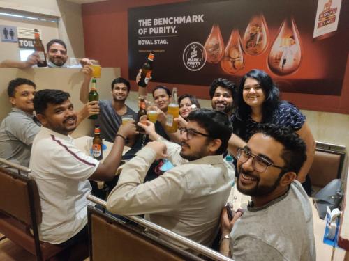 a group of people posing for a picture with beer at Nap Manor Hostels in Mumbai