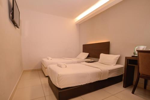 two beds in a small room with a table and chairs at GM Hotel Metro at Sunway in Petaling Jaya