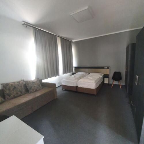 a living room with a bed and a couch at No Stress Panzió-Pizzéria-Sporttábor in Harkány