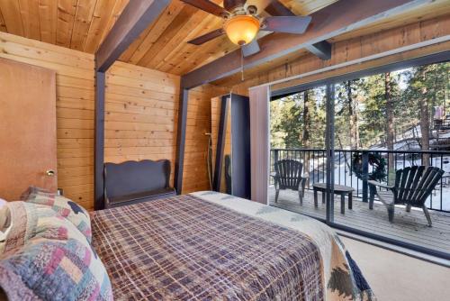ein Schlafzimmer mit einem Bett und einem großen Fenster in der Unterkunft Wolf Cub Cabin - 1946 by Big Bear Vacations in Big Bear Lake