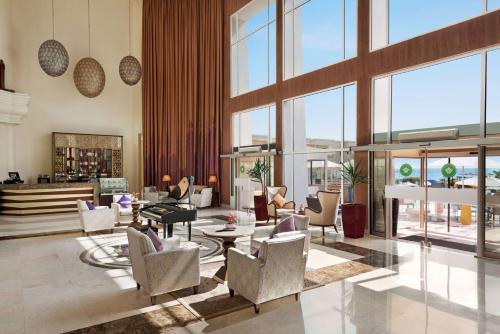 a lobby with chairs and tables and windows at Wyndham Garden Salalah Mirbat in Salalah