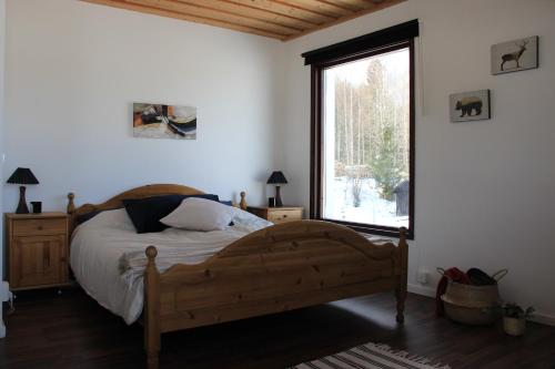 1 dormitorio con cama de madera y ventana grande en Lakeview Houses Sweden - Red House, en Svärdsjö