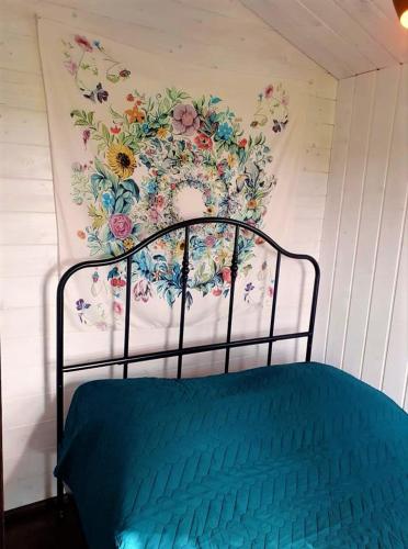 a bed in a room with a flower mural on the wall at Kiszkowianka domki in Skrzeszewo