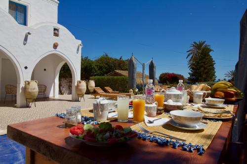 a table with food and fruit on a patio at Villa Calma - Vue Mer in Al Ḩaddādah