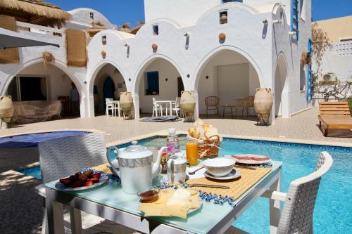 a table with food on it next to a pool at Villa Calma - Vue Mer in Al Ḩaddādah