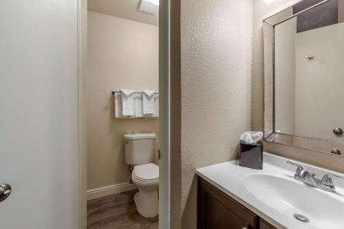 a bathroom with a toilet and a sink with a mirror at Rodeway Inn & Suites in Ontario