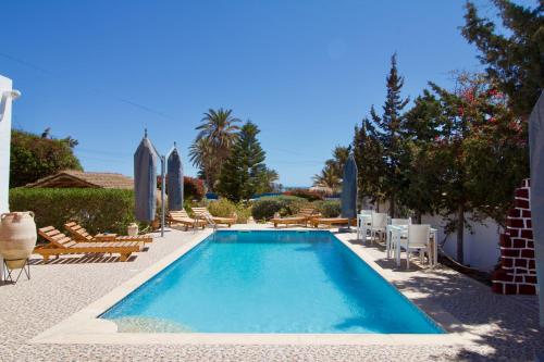 a swimming pool with chaise lounge chairs and umbrellas at Villa Calma - Vue Mer in Al Ḩaddādah