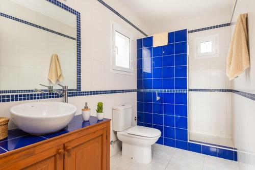 a blue and white bathroom with a sink and a toilet at Villa Spring Hill - Cala Galdana in Ferreries