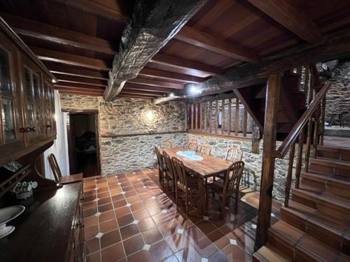 Un comedor con una mesa y una pared de piedra. en Casa Torres, en Cruces