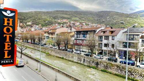 a city with cars parked on a street next to a river at Hotel Perla in Prizren