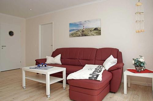 sala de estar con sofá rojo y mesa en Rotesand en Cuxhaven