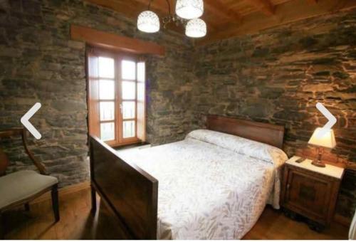 ein Schlafzimmer mit einem Bett und einer Steinmauer in der Unterkunft Casa con encanto in Cedeira
