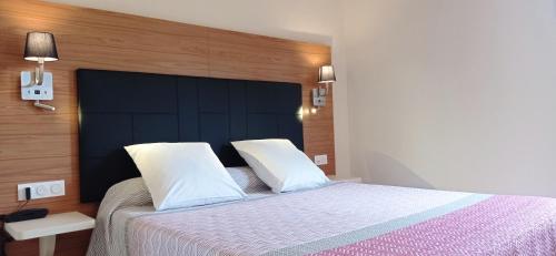 a bedroom with a large bed with a black headboard at Hotel Hélios in Cap d'Agde