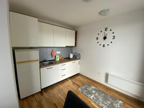 a kitchen with white cabinets and a clock on the wall at Apartman "AROMA 1"Bjelasnica in Bjelašnica