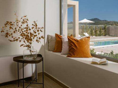 a window seat with pillows and a table with a book at Chrysothemis Villas in Pigadhákia