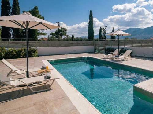 a swimming pool with two chairs and an umbrella at Chrysothemis Villas in Pigadhákia