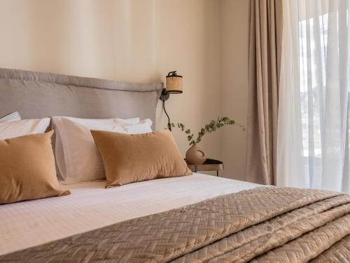 a bedroom with a bed with white sheets and a window at Chrysothemis Villas in Pigadhákia